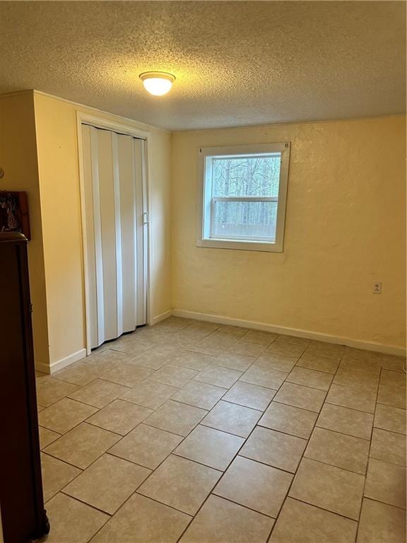 tiled empty room featuring a textured ceiling