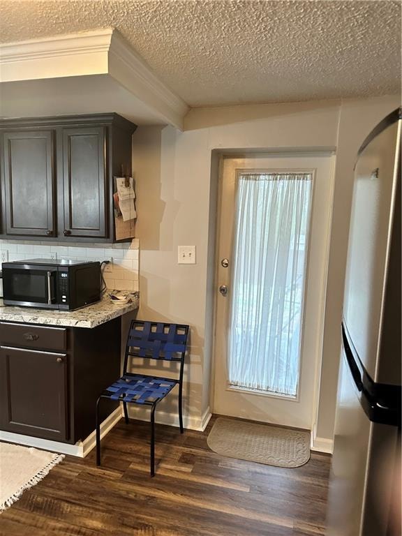 kitchen featuring light stone countertops, dark hardwood / wood-style floors, dark brown cabinets, tasteful backsplash, and a textured ceiling