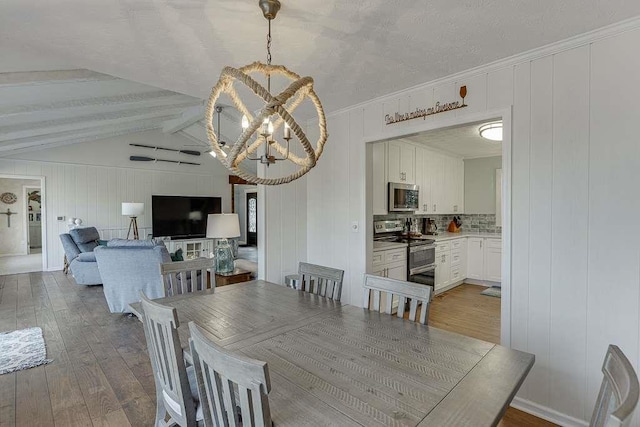 dining space with an inviting chandelier, hardwood / wood-style floors, and lofted ceiling with beams