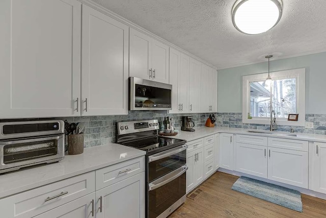 kitchen featuring stainless steel appliances, light hardwood / wood-style floors, sink, and white cabinets