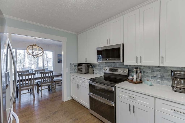 kitchen featuring white cabinetry, a notable chandelier, stainless steel appliances, and light wood-type flooring