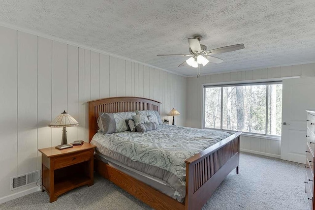 bedroom with light carpet, a textured ceiling, crown molding, and ceiling fan