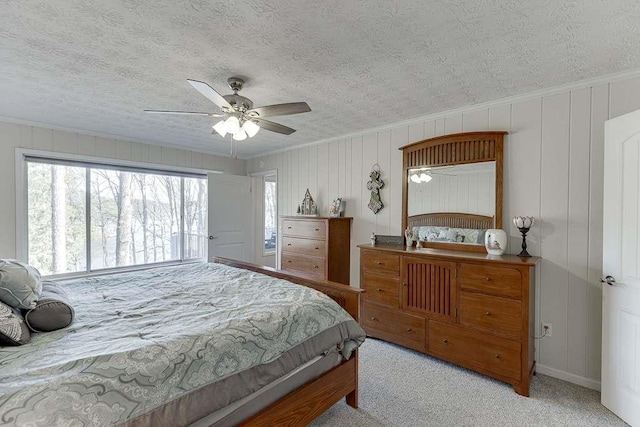 carpeted bedroom with ceiling fan, ornamental molding, and a textured ceiling