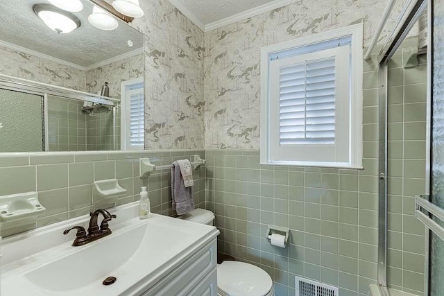 bathroom with vanity, ornamental molding, a textured ceiling, a shower with shower door, and toilet