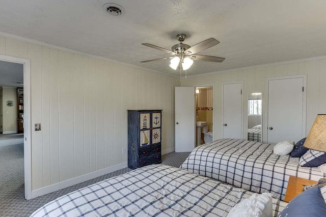 carpeted bedroom featuring ornamental molding, ceiling fan, and a textured ceiling