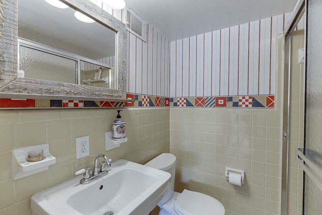 bathroom with tile walls, sink, toilet, and an enclosed shower