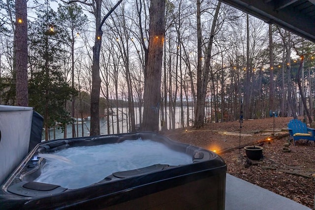 yard at dusk featuring a hot tub and a water view