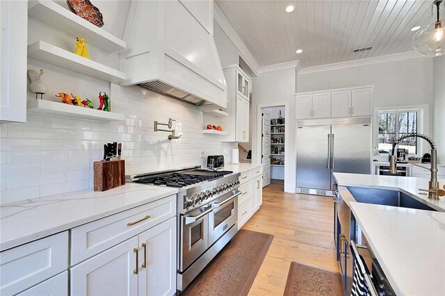 1455 Rucker Cir, Woodstock, GA 30188 - kitchen featuring premium appliances, custom range hood, white cabinets, ornamental molding, and recessed lighting