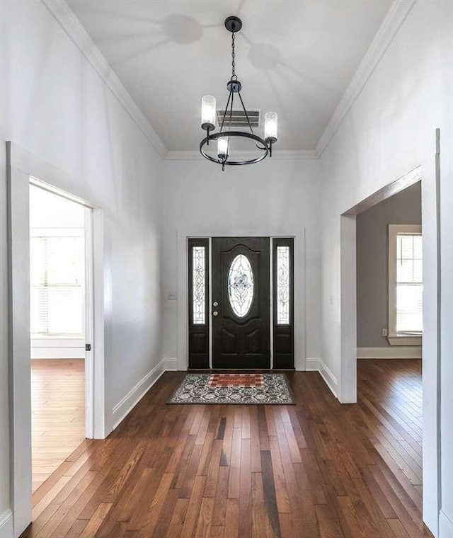 entrance foyer featuring crown molding, dark hardwood / wood-style flooring, and a chandelier