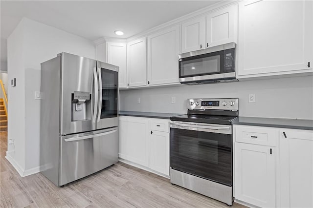 1974 Browns Mill Rd SE, Atlanta, GA 30315 - kitchen featuring appliances with stainless steel finishes, light wood-style floors, white cabinetry, dark countertops, and recessed lighting