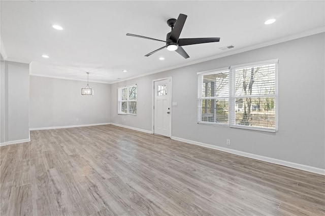 unfurnished living room featuring a healthy amount of sunlight, ornamental molding, ceiling fan with notable chandelier, and light hardwood / wood-style flooring