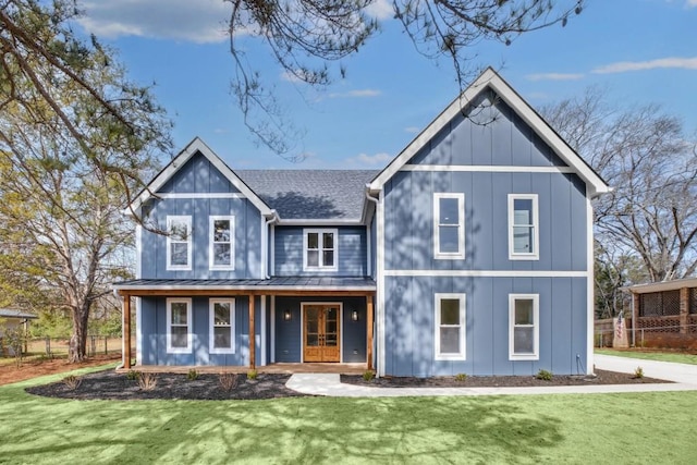 view of front facade featuring a shingled roof, a standing seam roof, metal roof, and a front lawn