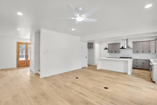 474 Maxwell Rd, Roswell, GA 30075 - kitchen featuring wall chimney range hood, gray cabinets, light countertops, tasteful backsplash, and light wood-style flooring