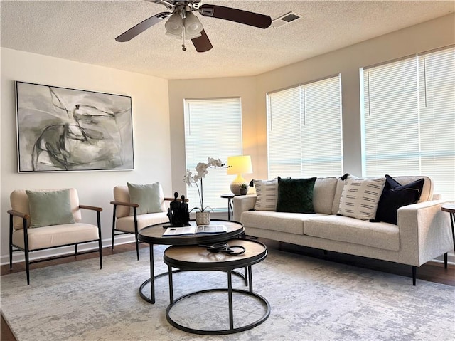 living room featuring a textured ceiling, hardwood / wood-style floors, and ceiling fan