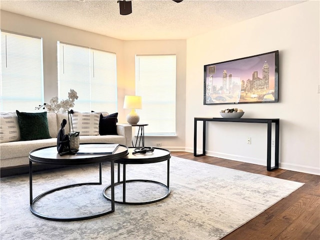 living room with ceiling fan, dark hardwood / wood-style flooring, and a textured ceiling