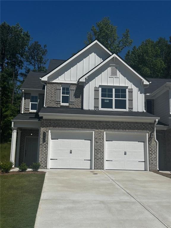 view of front of property featuring a garage, concrete driveway, board and batten siding, and brick siding