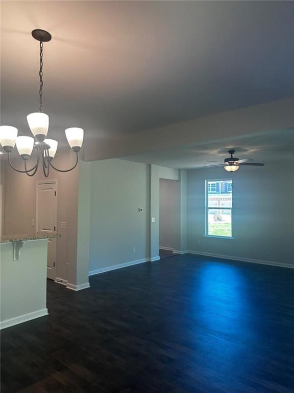 empty room with dark wood finished floors, baseboards, ceiling fan, and a chandelier