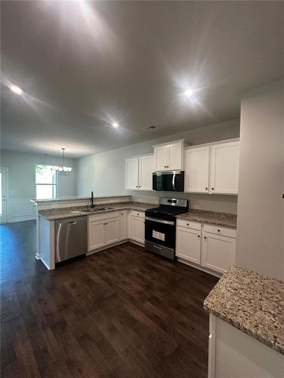 kitchen featuring stainless steel appliances, dark wood-style flooring, a sink, a peninsula, and white cabinetry