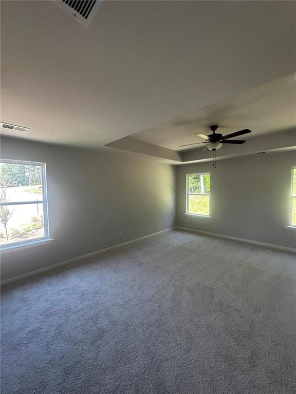 carpeted empty room with baseboards, ceiling fan, and a tray ceiling