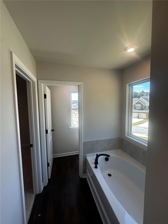 full bathroom with a bath, wood finished floors, and baseboards