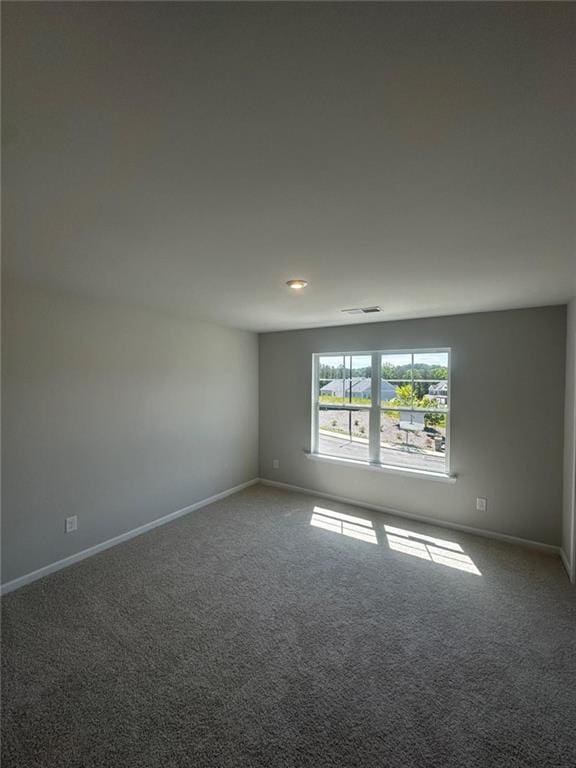carpeted spare room featuring baseboards