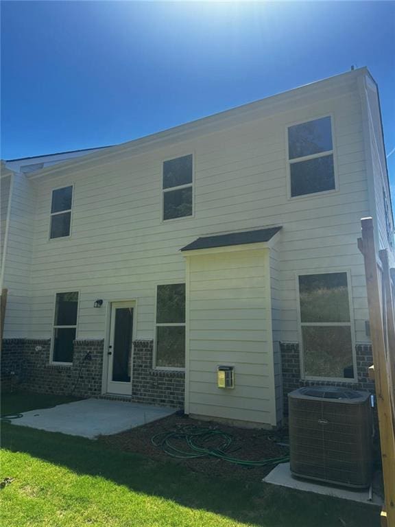 rear view of house with cooling unit, a patio area, and a yard