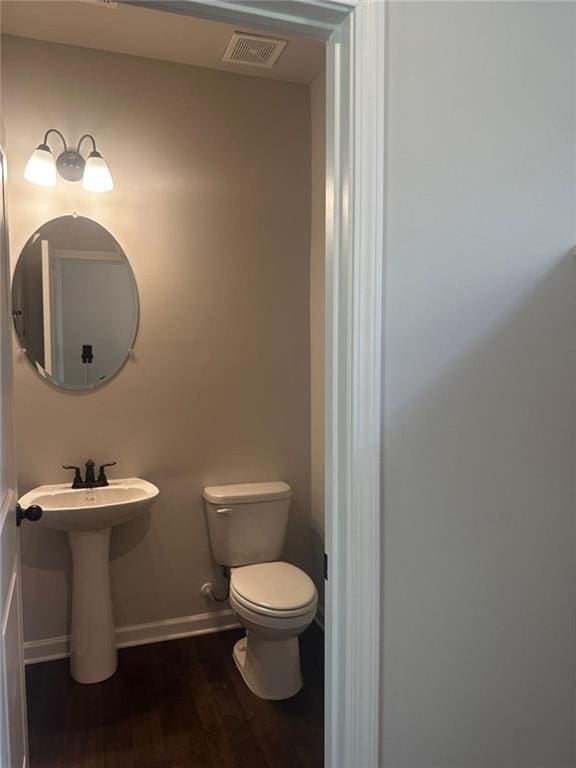half bath featuring toilet, wood finished floors, and baseboards