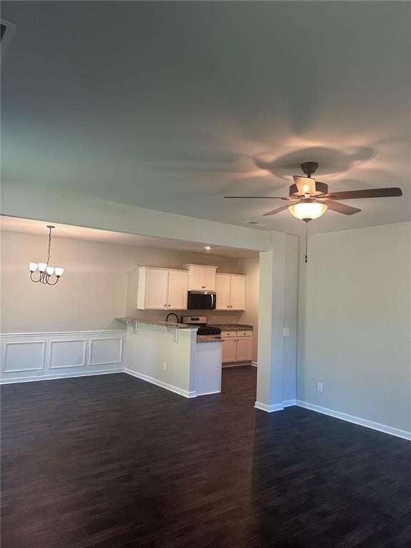 kitchen featuring appliances with stainless steel finishes, a peninsula, a kitchen breakfast bar, white cabinets, and dark wood-type flooring