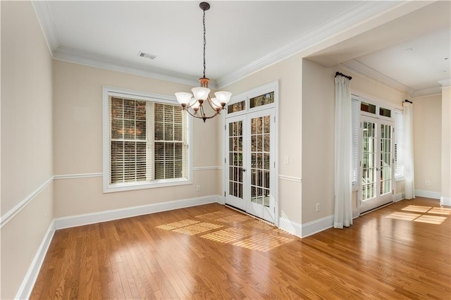 unfurnished dining area featuring french doors, crown molding, a chandelier, and hardwood / wood-style flooring