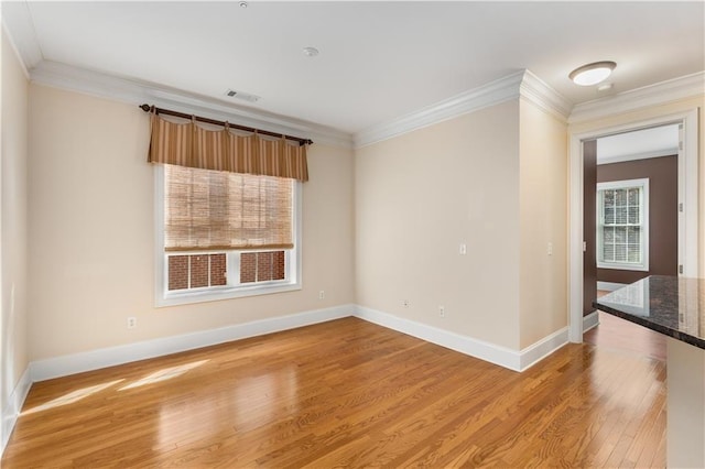 empty room featuring ornamental molding, light wood-style flooring, and baseboards