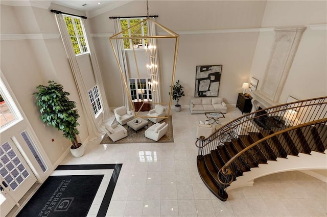 stairs featuring a towering ceiling, a chandelier, crown molding, tile patterned floors, and inlaid floor details