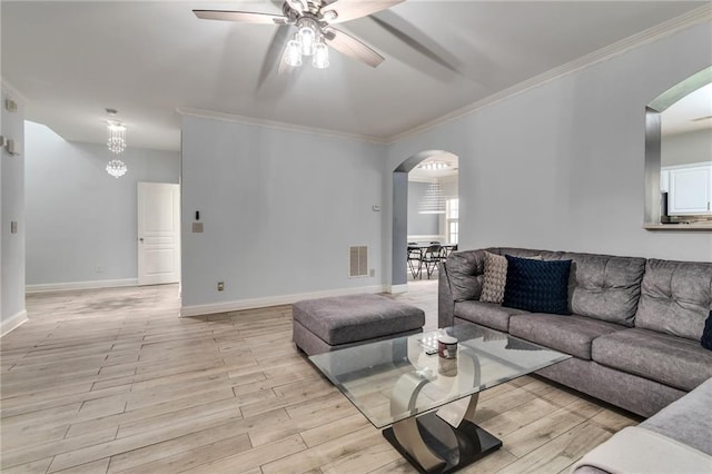 living area featuring light wood finished floors, visible vents, arched walkways, ceiling fan, and ornamental molding