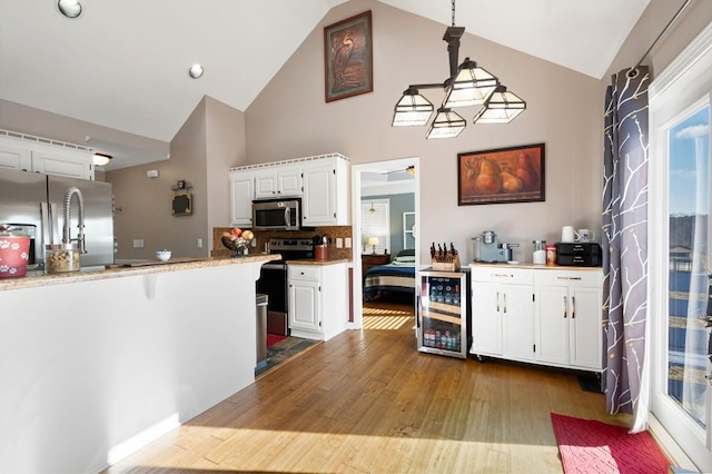 kitchen with hanging light fixtures, white cabinets, stainless steel appliances, and wine cooler