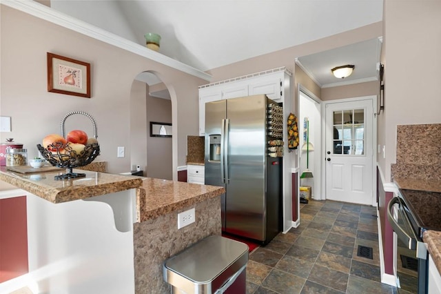 kitchen featuring white cabinetry, a kitchen breakfast bar, stainless steel fridge, kitchen peninsula, and vaulted ceiling