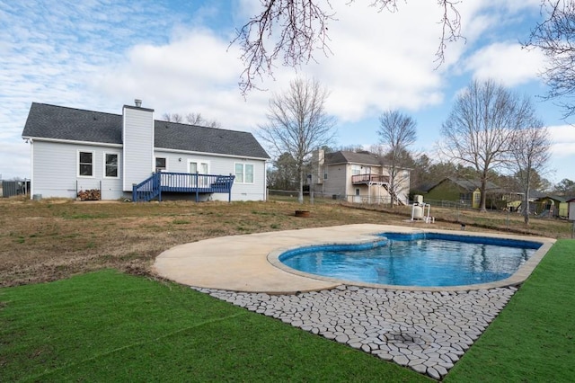 view of pool featuring a wooden deck, a lawn, and a patio