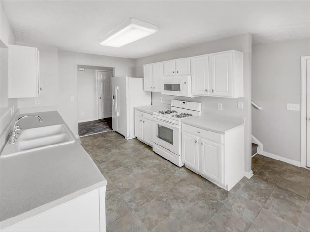 kitchen featuring sink, white appliances, and white cabinetry