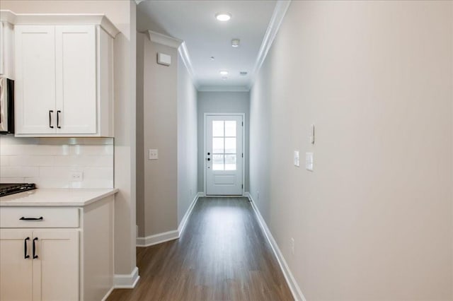 entryway featuring ornamental molding, dark wood-type flooring, and baseboards