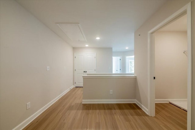 empty room featuring attic access, light wood finished floors, baseboards, and recessed lighting