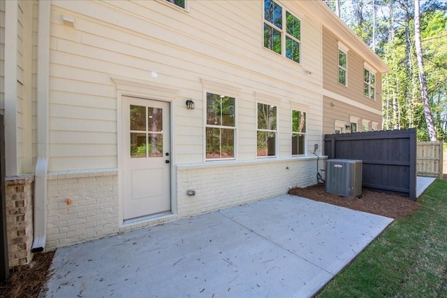 rear view of house with central AC, a patio, and brick siding