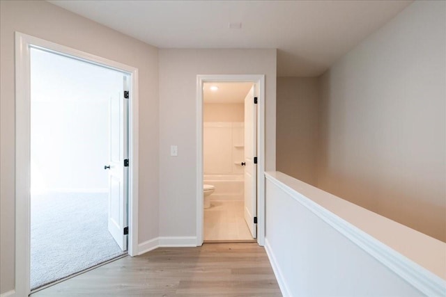 corridor with light wood finished floors and baseboards