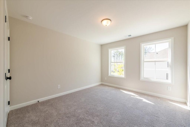carpeted empty room featuring baseboards and a smoke detector