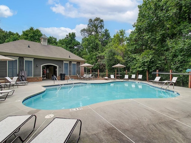 community pool featuring a patio area and view of scattered trees