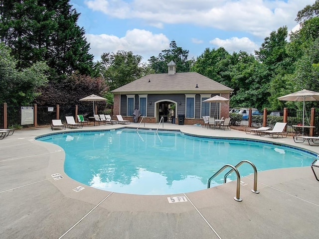 community pool with a patio area and view of scattered trees