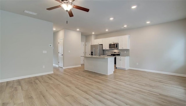 kitchen featuring light hardwood / wood-style floors, white cabinetry, a kitchen island with sink, and appliances with stainless steel finishes