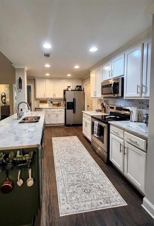 kitchen featuring a center island with sink, sink, dark hardwood / wood-style floors, appliances with stainless steel finishes, and white cabinetry