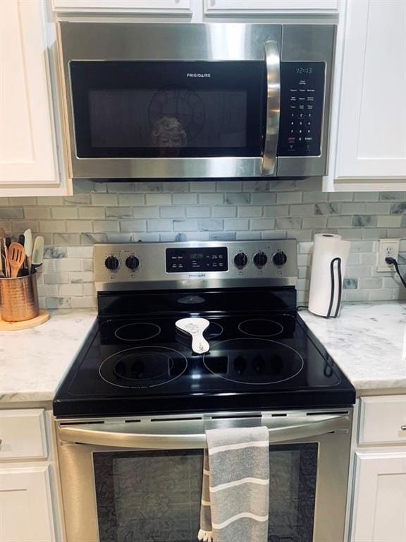 kitchen with light stone countertops, white cabinetry, appliances with stainless steel finishes, and tasteful backsplash