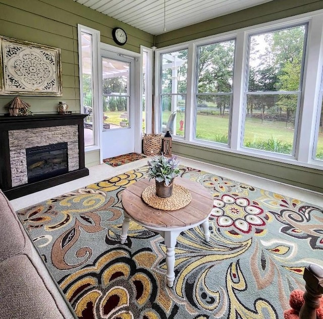 sunroom / solarium with plenty of natural light and a stone fireplace