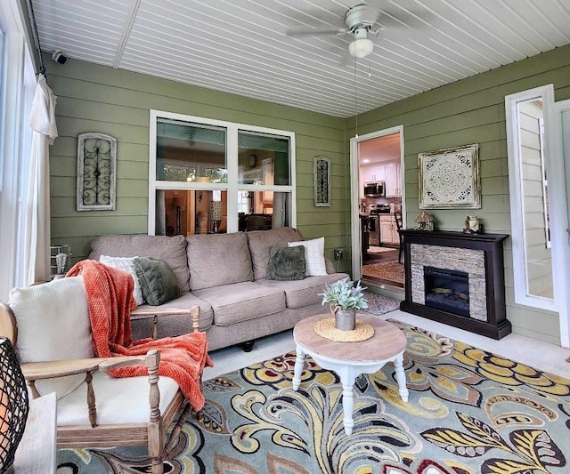 living room with wooden walls, a fireplace, and ceiling fan