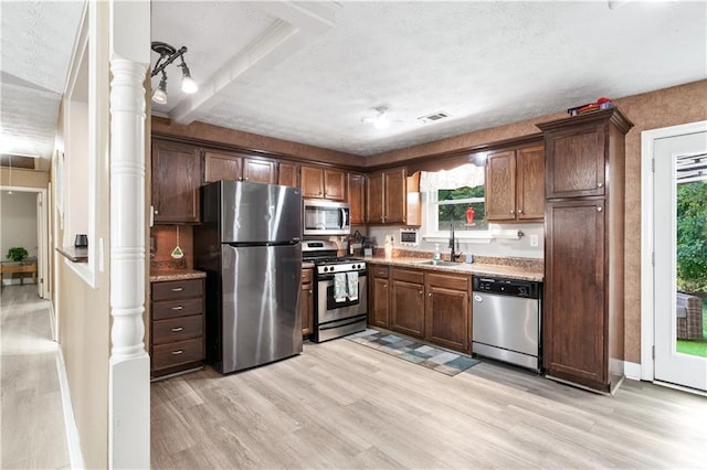 kitchen featuring appliances with stainless steel finishes, light wood-type flooring, dark brown cabinets, a textured ceiling, and sink