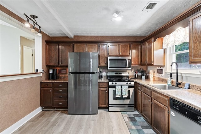 kitchen with sink, light wood-type flooring, ornamental molding, beamed ceiling, and stainless steel appliances